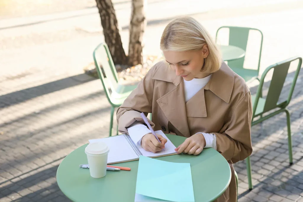 portrait woman working project writing notebook sitting outdoors cafe drinking coffee